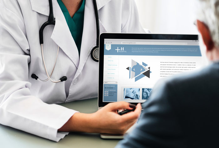 A medical assistant showing a patient an image on a laptop during a clinical process.