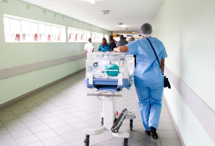A medical student walking down a hallway with a cart