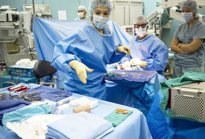 A surgical tech in an operating room with doctors.