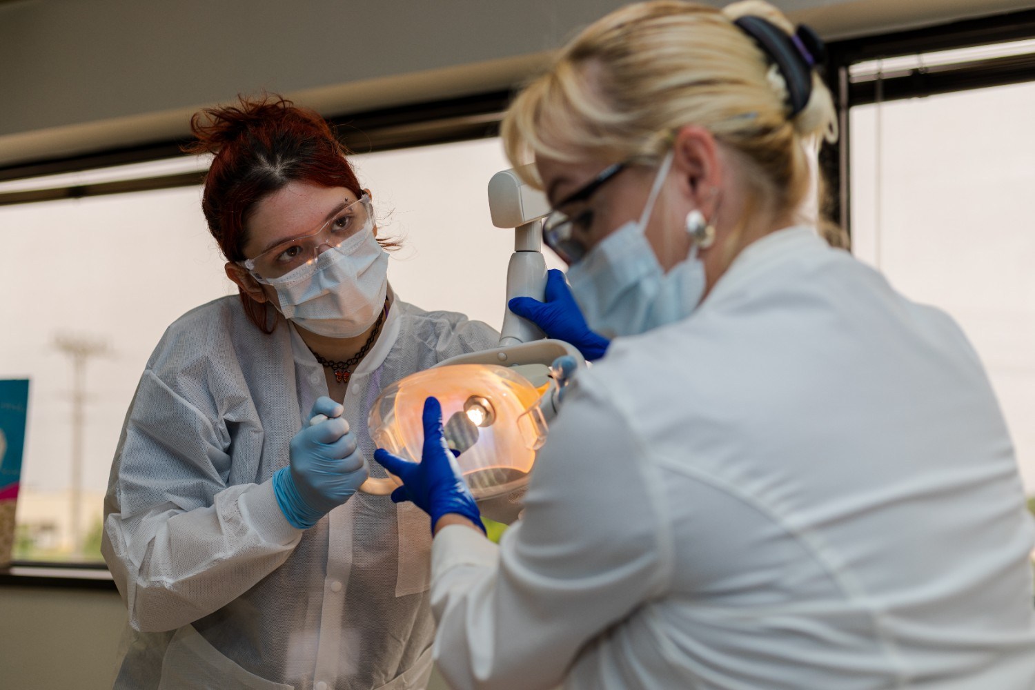 Dental Assistant student looking at instructor, who is holding a dental exam light