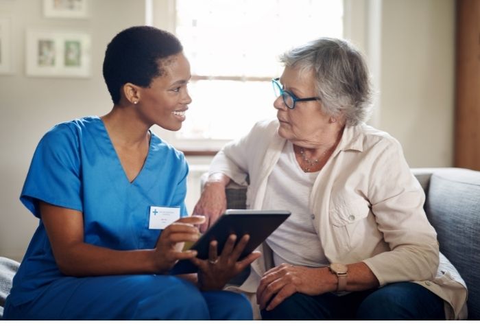 Medical assistant sits with elderly patient