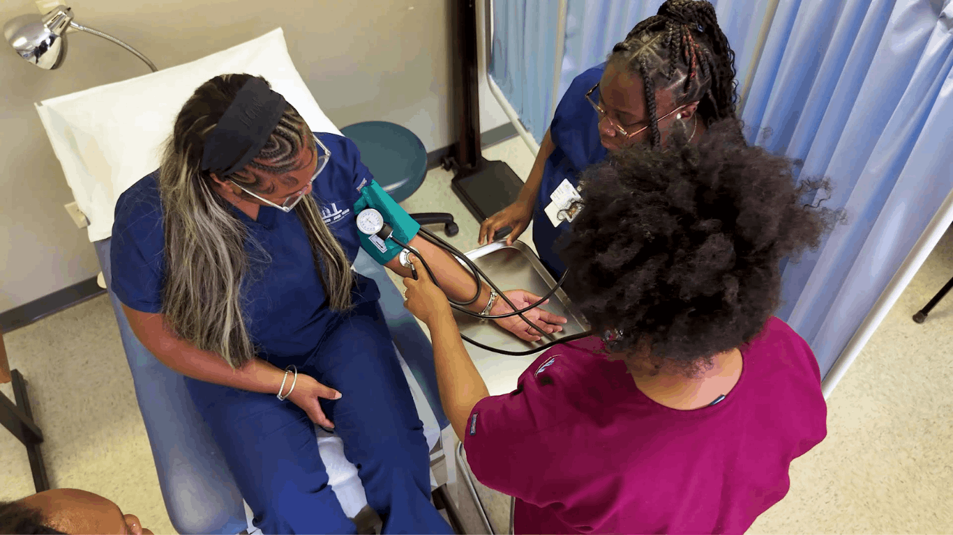 Two Medical Assistant students putting a blood pressure band on a student